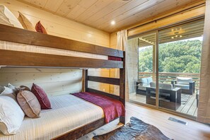 A bunk bed with pillows and a blanket, a wooden ceiling, and a balcony with outdoor furniture. - Brand-New Smokies Cabin w/ Spectacular Mtn Views (Sevierville)