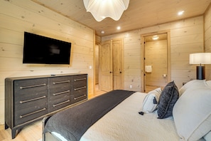 Ein Schlafzimmer mit einem Bett, einem Schminktisch, einem an der Wand befestigten Fernseher und Holztüren.