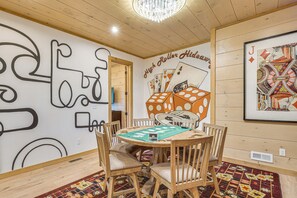 A room with a wooden ceiling, a chandelier, a poker table with cards, and a wall with abstract art. - Brand-New Smokies Cabin w/ Spectacular Mtn Views (Sevierville)