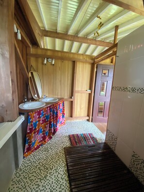 A wooden interior with a bathroom featuring two sinks, a mirror, and a patterned floor.