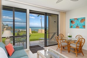 Ein modernes Wohnzimmer mit Glastür, die auf einen Balkon mit Meerblick führt.