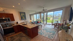 A modern kitchen with stainless steel appliances, a large island, and a dining area with a view of the outdoors. - Ocean Views, Steps to Turtle Snorkeling at Honokeana Cove -Napili Point B24 (Lahaina)