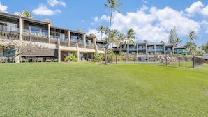 A hotel with multiple balconies, outdoor seating, and palm trees. - Ocean Views, Steps to Turtle Snorkeling at Honokeana Cove -Napili Point B24 (Lahaina)