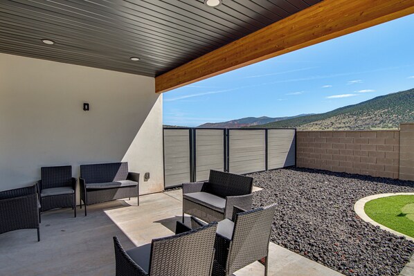 Eine Terrasse im Freien mit Korbmöbeln und Blick auf eine gebirgige Landschaft.