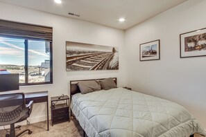 A bedroom with a bed, a desk, a chair, and a window with a view of a landscape. - Game Room & Stunning Mtn Views! Cedar City Home (Cedar City)