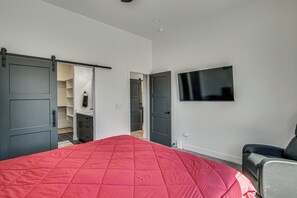 Une chambre à coucher avec un lit, un téléviseur fixé au mur et un placard à portes coulissantes.