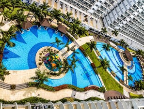 A large hotel with multiple swimming pools, palm trees, and a modern architectural design. - Centrally-Located, Comfortable Apartment in Pasay (Pasay)