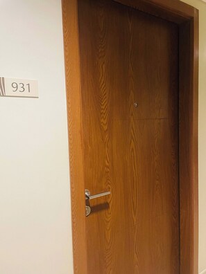 Una puerta de madera con un picaporte de metal y un cartel blanco con el número 931.