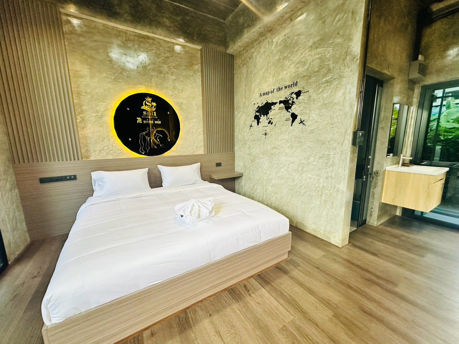 A modern hotel room with a large bed, a wall-mounted globe, and a wooden vanity.