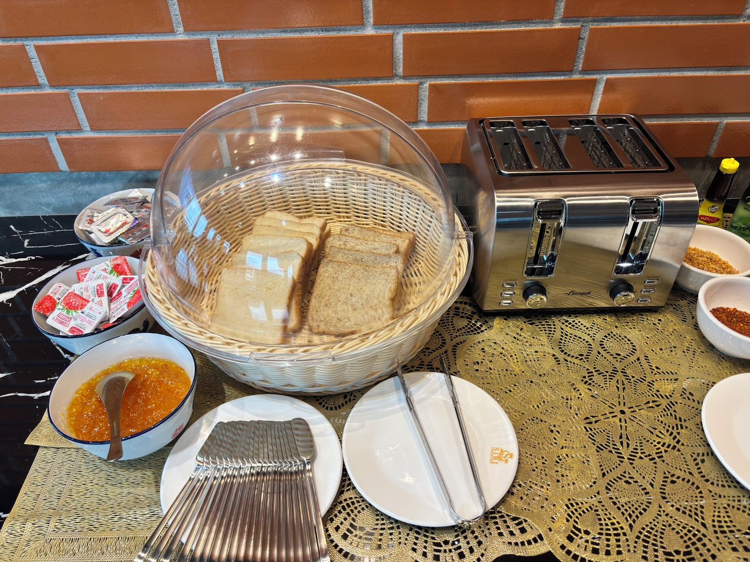 A kitchen counter with a toaster, a basket of bread, and various condiments.