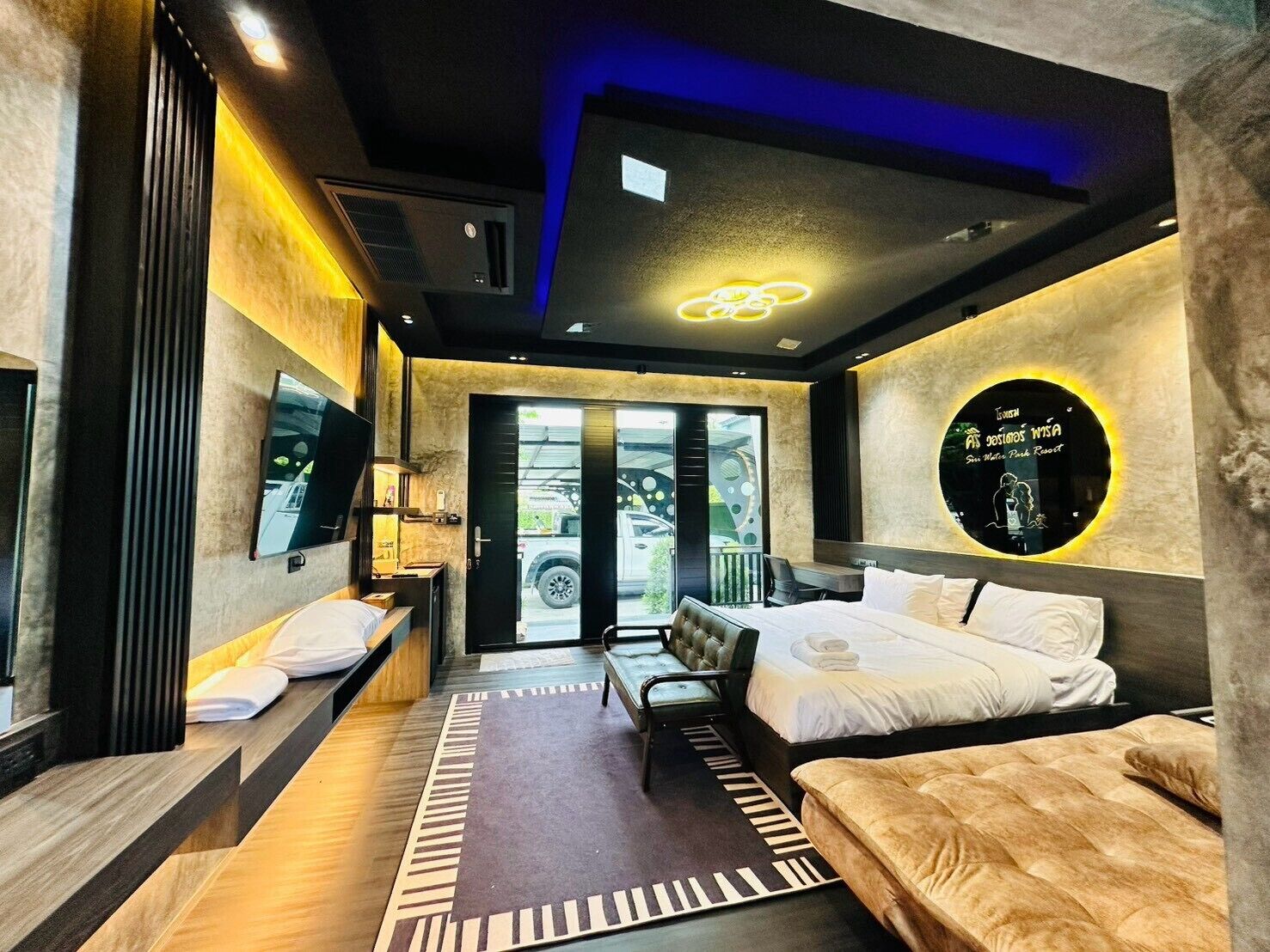 A modern hotel room with a bed, seating area, and a television.