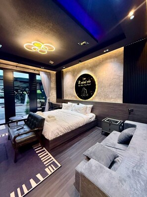 A modern bedroom with a large bed, a sofa, a desk, and a view of the outdoors. - Siri Water Park & Resort (Lamphun)