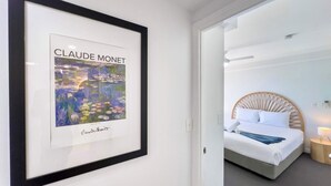 Et indrammet kunstværk af Claude Monet i et hotelværelse med en seng og et natbord.