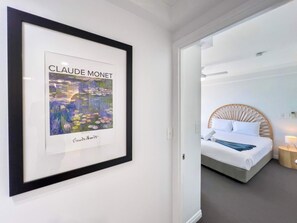 Ein gerahmtes Gemälde von Claude Monet in einem Hotelzimmer mit Bett und Nachttisch.
