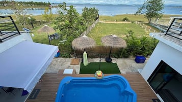 A rooftop pool with a view of a lake and distant mountains.