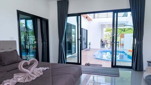 Camera da letto moderna con un letto grande, una porta vetrata che dà su un balcone con piscina.