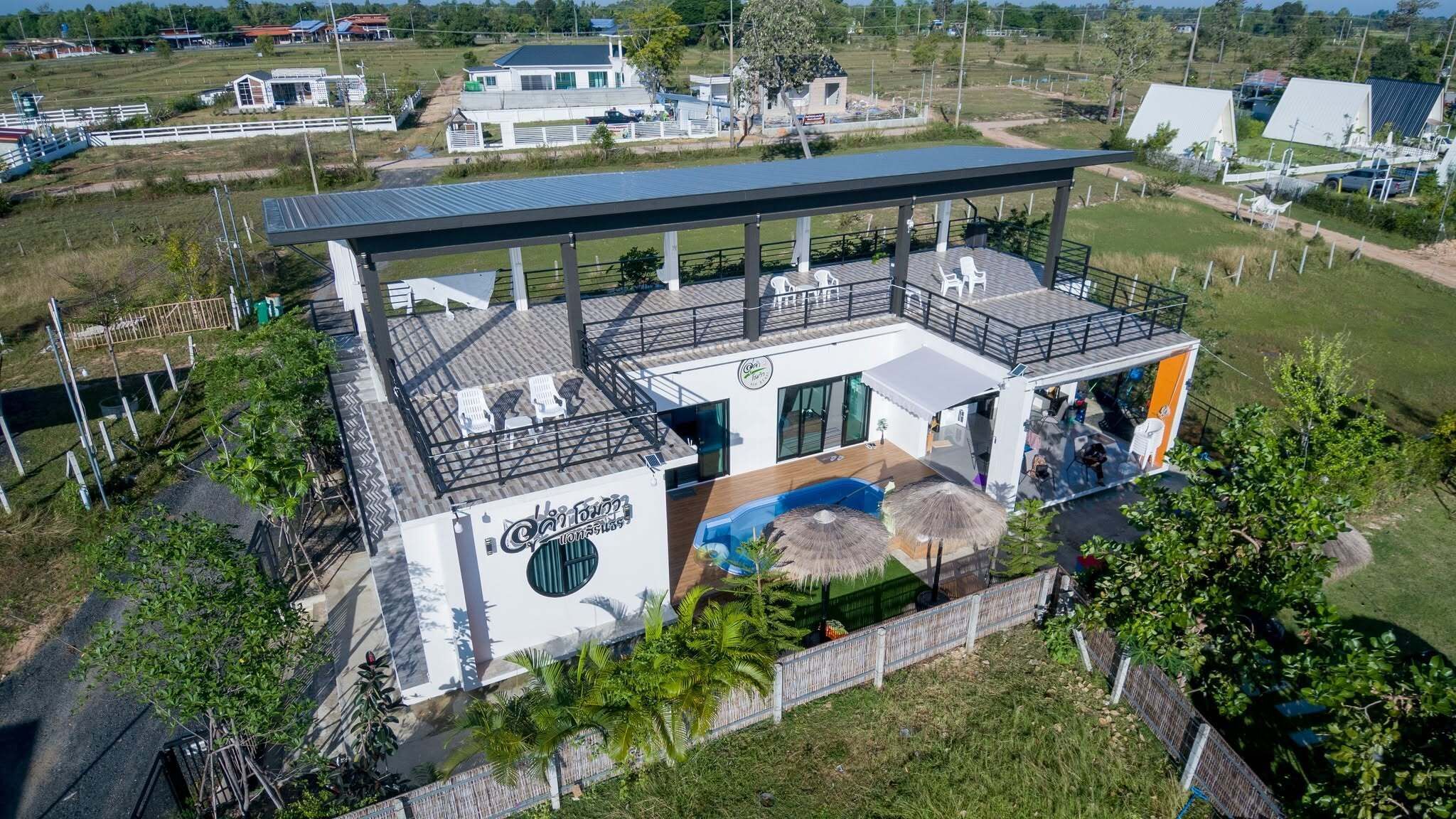 Un edificio moderno con un patio cubierto, una piscina y vistas del paisaje circundante.