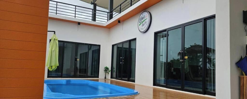Ein moderner, überdachter Schwimmbereich mit Glaswänden, einer Uhr und einem Balkon.