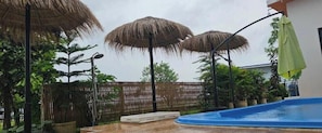 A swimming pool area with umbrellas and a wooden fence.