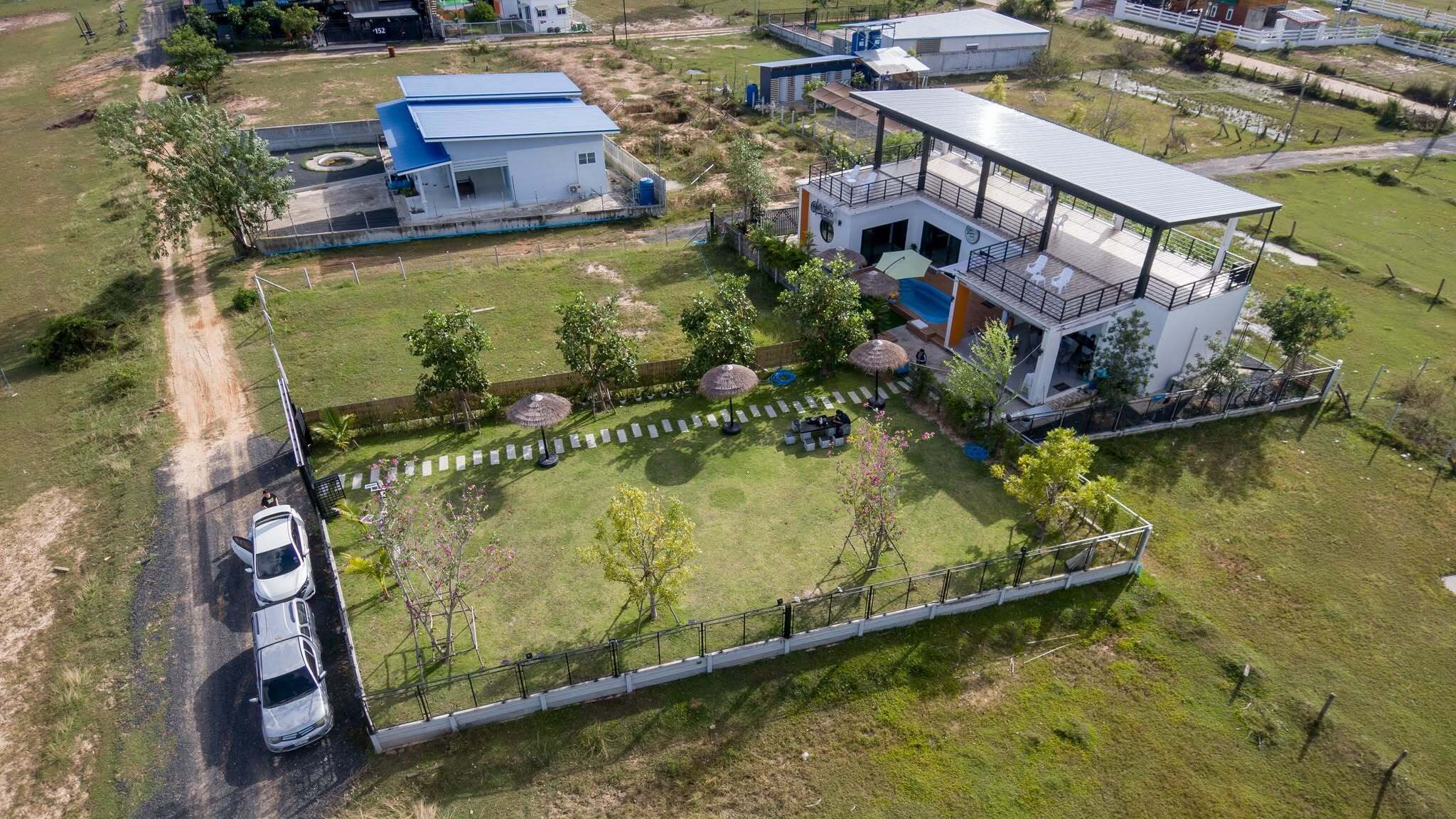 Una propiedad residencial con una casa grande, un jardín cercado y un automóvil estacionado.
