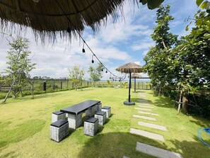 An outdoor patio with a thatched roof, string lights, and a view of the sea. - U-Kham Home View At Sirindhorn (Sirindhorn District)