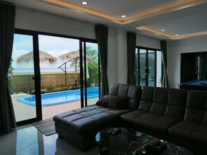 A modern living room with a sectional sofa, a pool, and a billiards table.