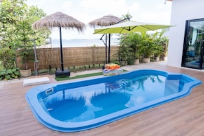 A swimming pool with a wooden deck, surrounded by potted plants and a bamboo fence. - U-Kham Home View At Sirindhorn (Sirindhorn District)