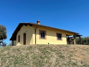 Une maison de plain-pied avec un toit en pente, une cheminée et un petit porche.