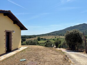A building with a brick entrance and a paved pathway leading to a rural landscape.