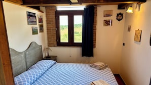 Une chambre à coucher avec un lit, une table de chevet, une fenêtre avec des rideaux et des éléments de décoration murale.