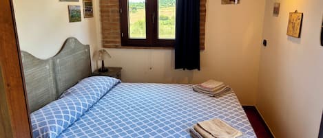 A bedroom with a bed, a nightstand, a window with curtains, and wall decorations.