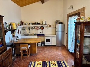 A kitchen with a wooden table, a sink, a stove, and a refrigerator.