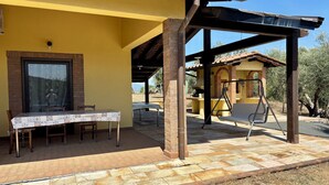 Un patio couvert comprenant une table et des chaises, un mur en briques et une structure en forme de pergola.