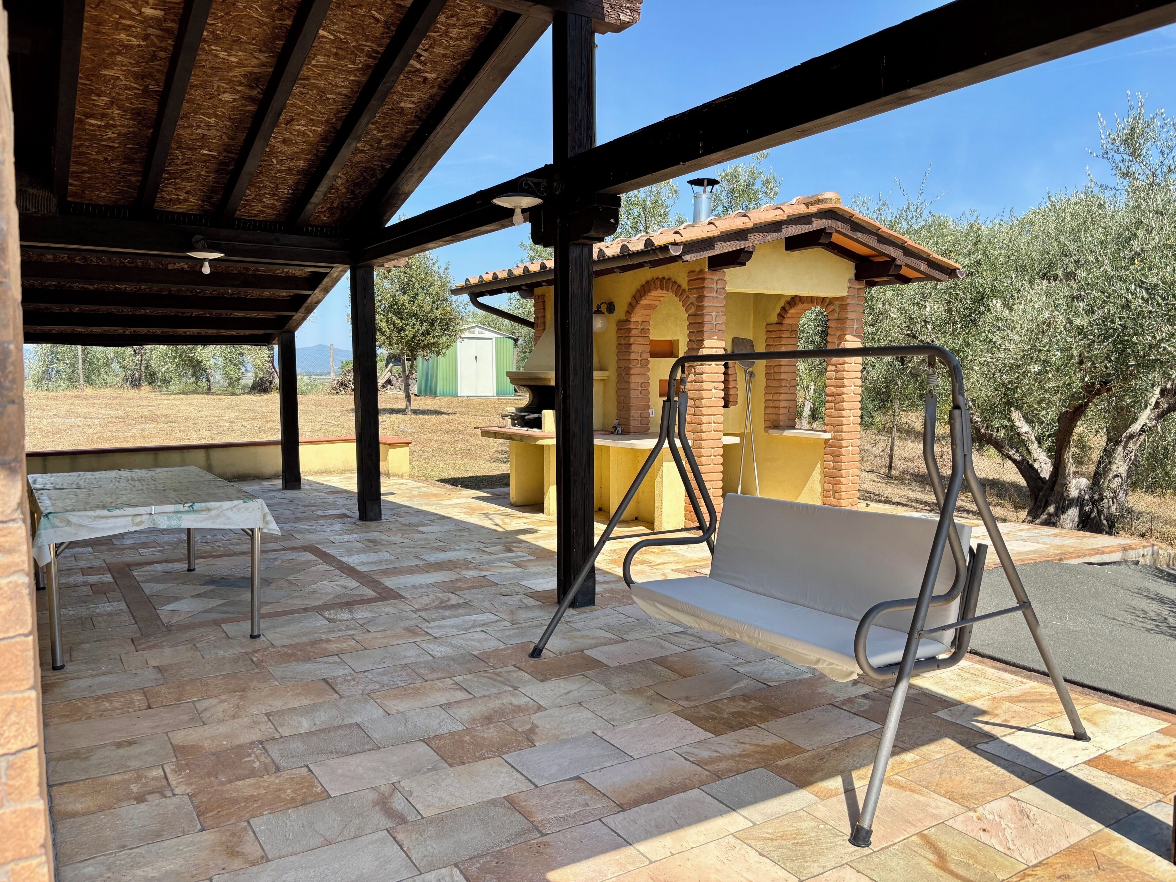 An outdoor patio with a covered area, a grill, and a table.