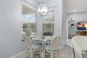 A dining area with a round glass table, white chairs, and a pendant light.