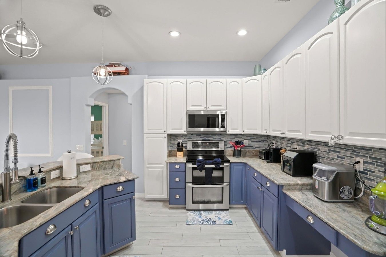 A modern kitchen with white cabinets, a stainless steel sink, and a built-in microwave.