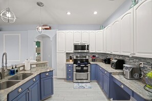 A modern kitchen with white cabinets, a stainless steel sink, and a built-in microwave.