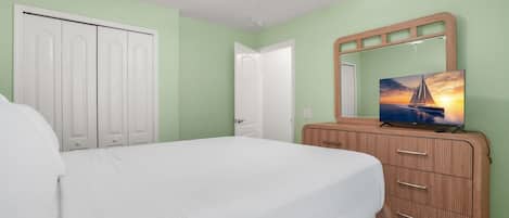 A bedroom with a bed, a dresser, a television, and a ceiling fan.