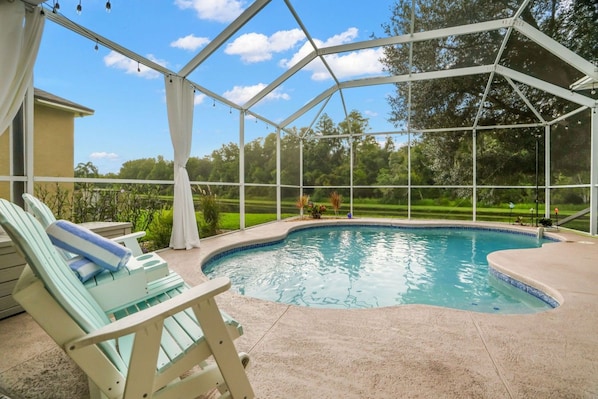 A covered outdoor swimming pool with lounge chairs and a view of a golf course.