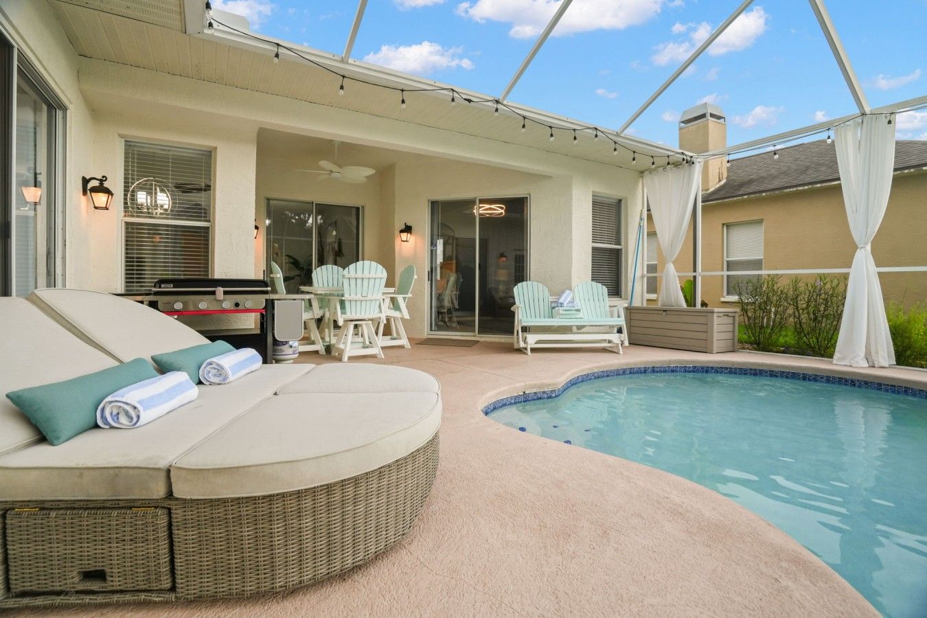 A covered outdoor area with a pool, lounge chairs, and a barbecue grill.