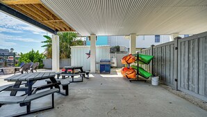 Eine Außenpatio mit Picknicktischen, einem Grill, Kajaks und einem überdachten Bereich mit Wellblechdach.