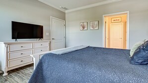 Ein Schlafzimmer mit Bett, Schminktisch, Fernseher und einer Tür.