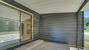 Eine überdachte Veranda mit Betonboden und einer Glastür, die zu einem Raum führt.