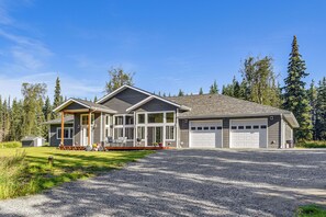 A two-story house with a covered porch, large windows, and a garage. - Exquisite Private Home Retreat Near Kenai River (Soldotna)