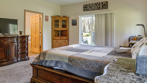 Ein Schlafzimmer mit einem großen Bett, Holzmöbeln, einem Fernseher und Blick ins Freie.
