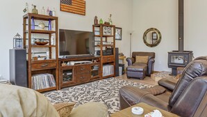 Ein Wohnzimmer mit einer Holztrennwand, einem Fernseher, einem Kamin und einer gemütlichen Sitzecke.