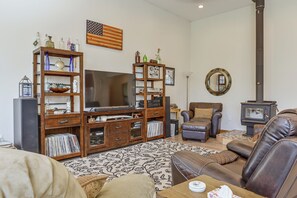 A living room with a wooden entertainment center, a television, a fireplace, and a comfortable seating area. - Exquisite Private Home Retreat Near Kenai River (Soldotna)