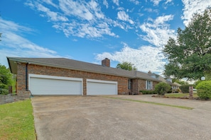 A two-story house with a brick facade, two attached garages, and a well-maintained lawn. - Backyard Oasis! Spacious Tulsa Home w/ Pool (Tulsa)