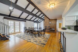 A spacious dining area with a large wooden table and chairs, a patterned rug, and a brick fireplace. - Backyard Oasis! Spacious Tulsa Home w/ Pool (Tulsa)