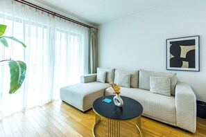 A modern living room with a sofa, a coffee table, and a potted plant. - Tyms 3BR 2BA Apt at Jing'an Maple Garden (Shanghai)